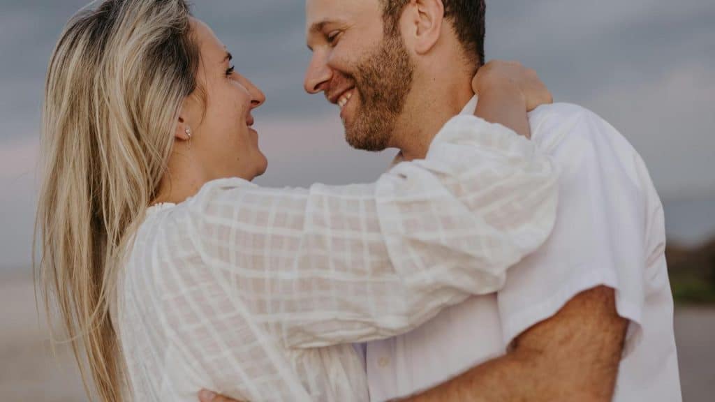 A couple embracing and smiling at each other on the beach.