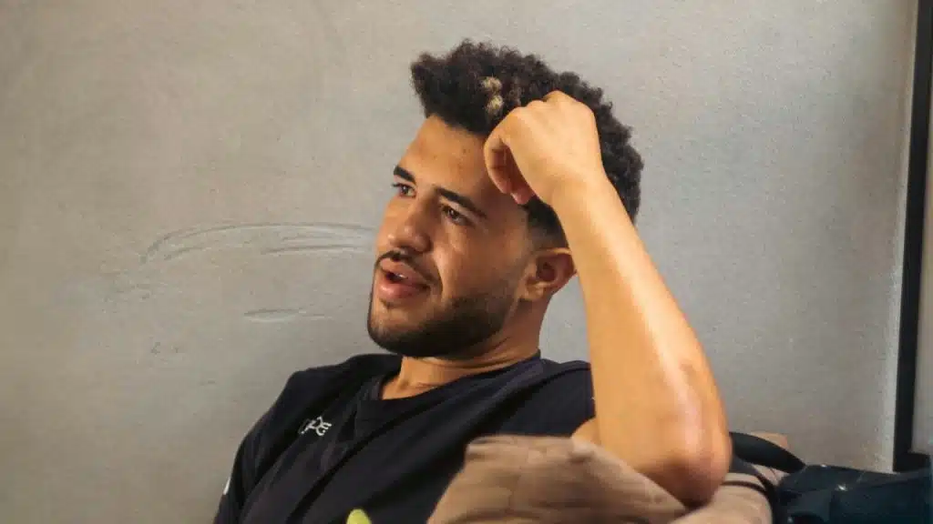 A man sitting on a couch with his hand on his head looking thoughtful.