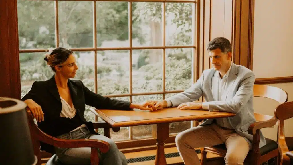 A man and a woman holding hands while sitting at a table.
