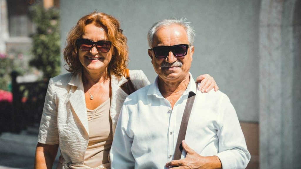 A senior couple is standing next to each other.