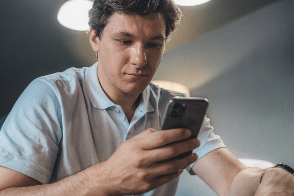 A Man in Blue Button Up Shirt Holding a Black Smartphone