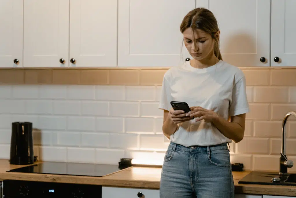 A woman using a phone in the kitchen
