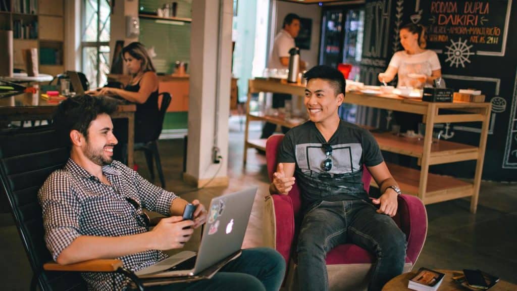A pair of people sitting and laughing together in a café or workspace.
