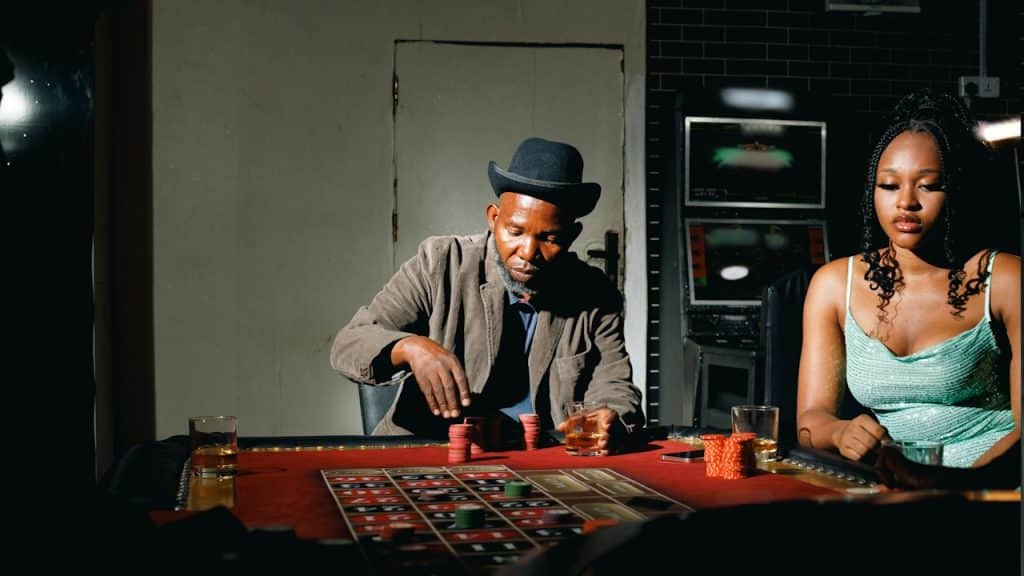 A man playing poker while his wife is sitting silently.