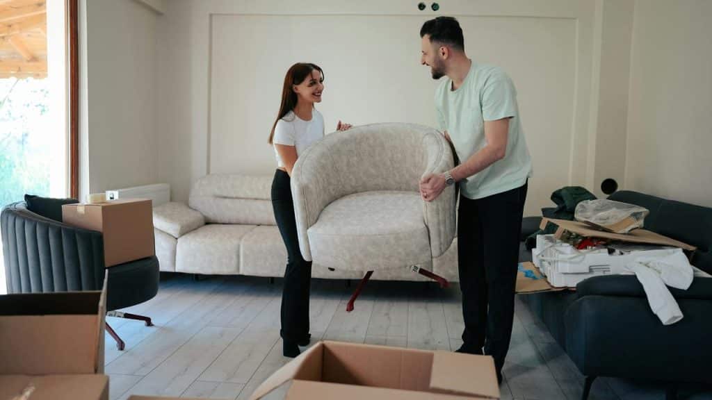 A couple lifting a chair together in the living room.