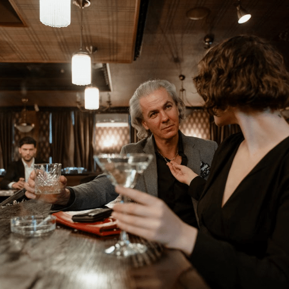 An older man talking to a younger woman in a bar