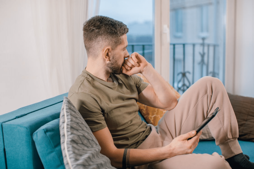 Man Sitting on Blue Couch Holding a Computer Tablet