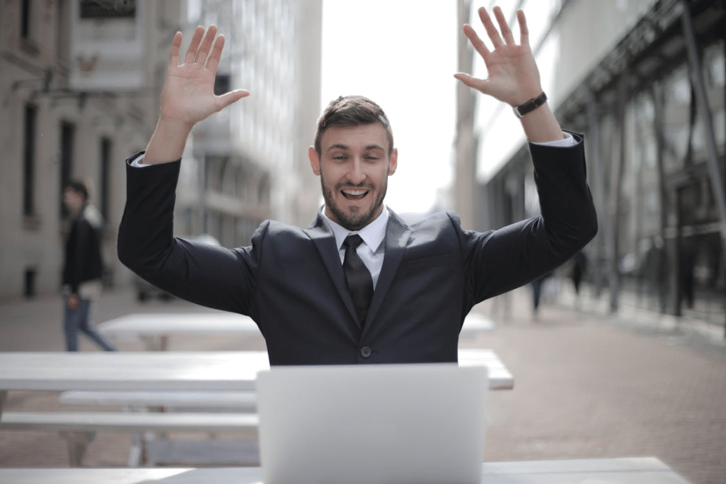 A man in a black suit raising both of his hands