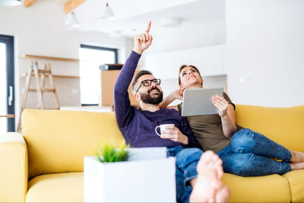 A man pointing at the ceiling to distract a woman
