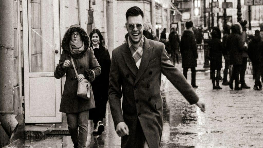 A cheerful man walking down a street.