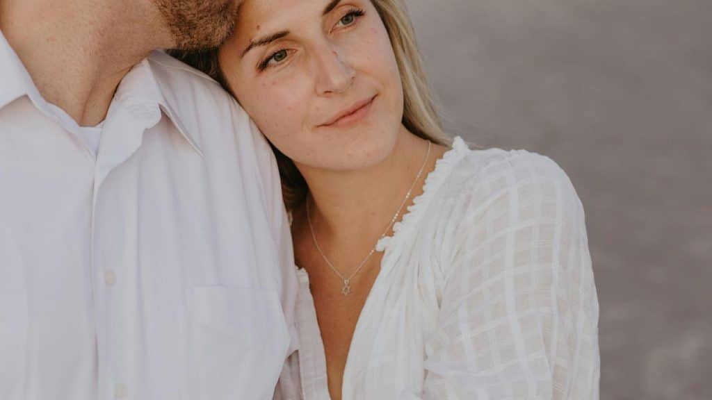 A woman resting her head on a man’s shoulder while gazing thoughtfully.