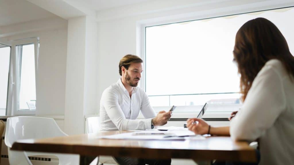 A man and woman sitting at a table during a meeting.