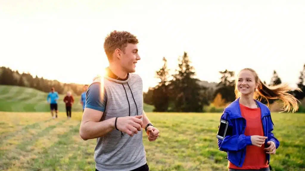 A couple running and smiling together outdoors.