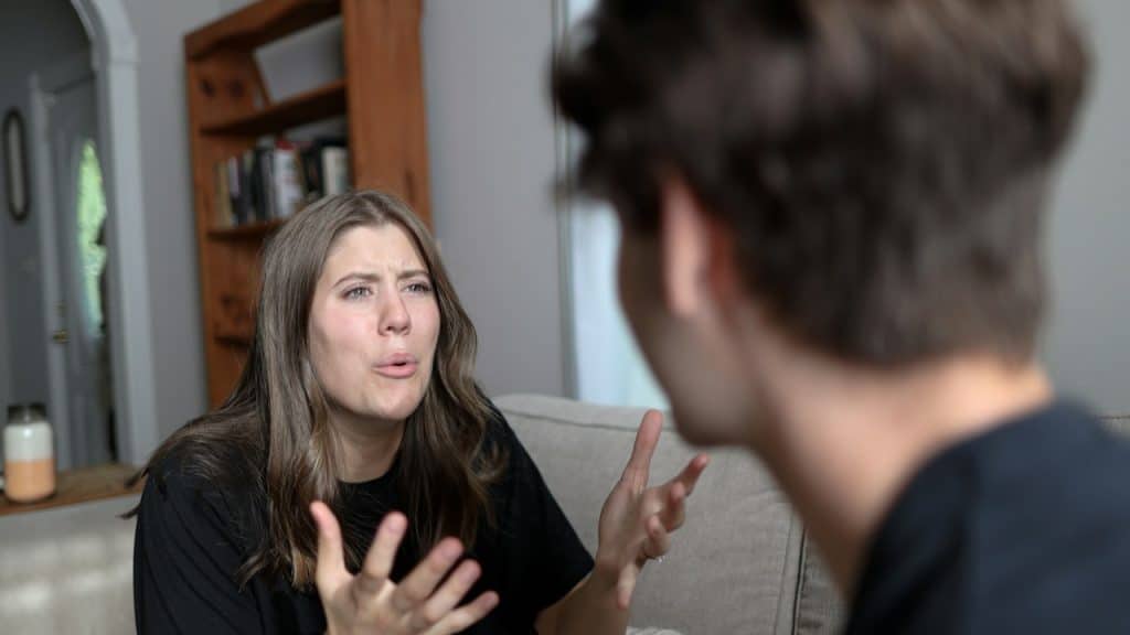A woman complaining to her husband while sitting with her husband.