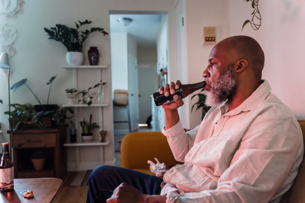 Man Sitting on Sofa Drinking Beer