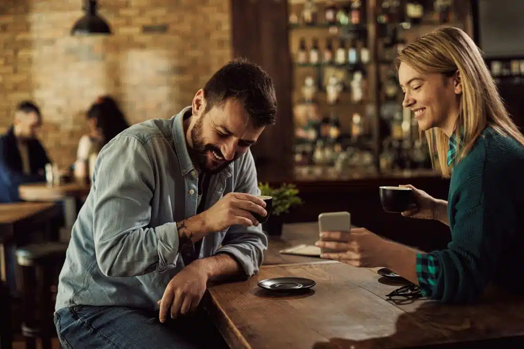 A couple reading something funny on a smartphone.