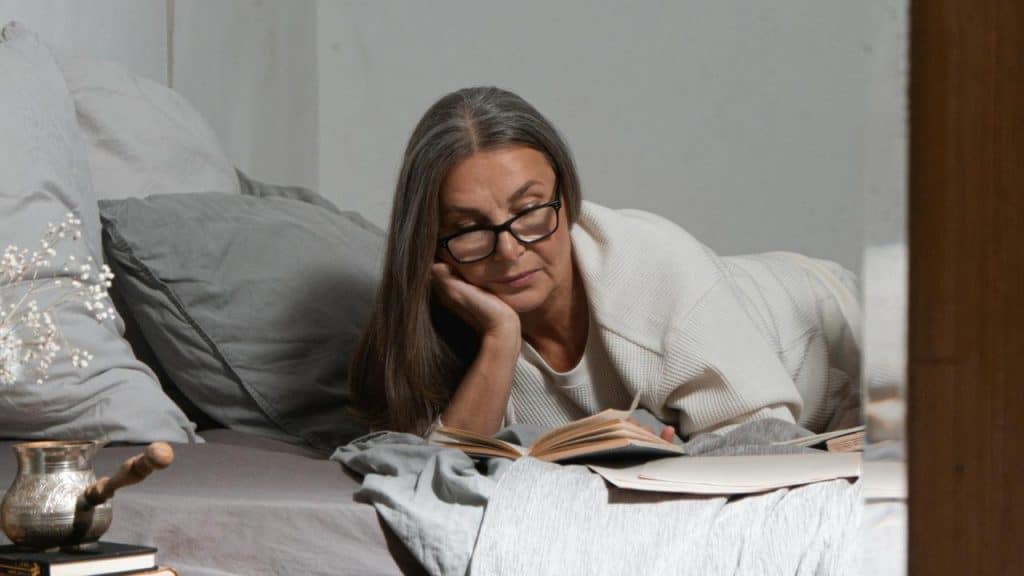 A woman lying in bed reading a book.