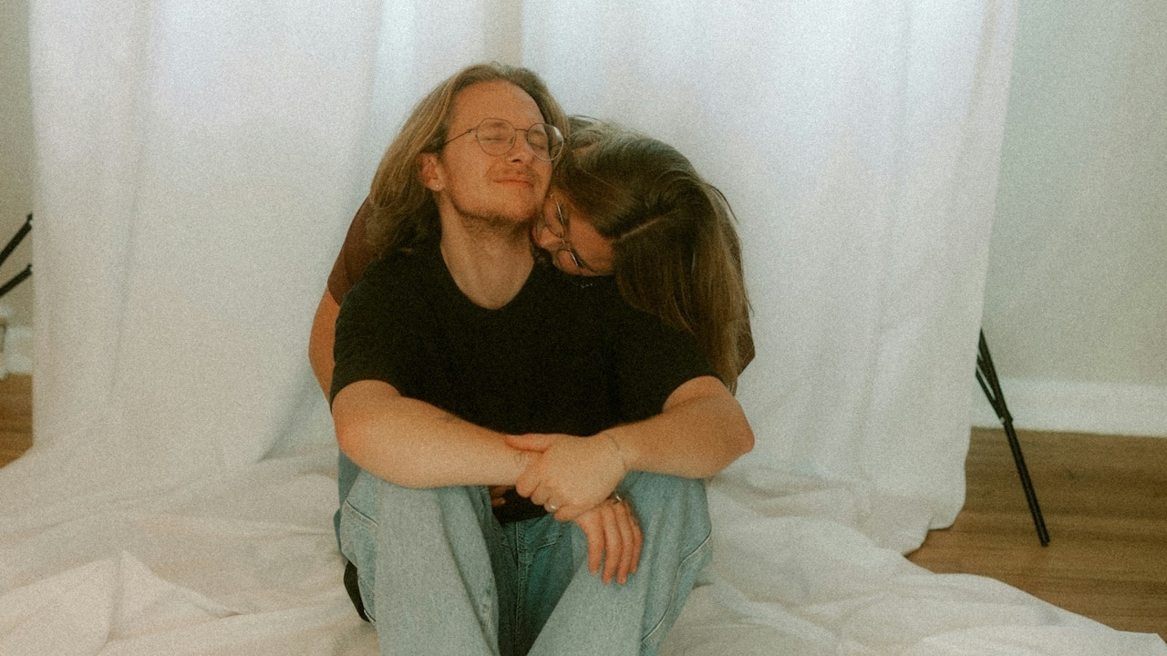 A woman is hugging his husband from behind.
