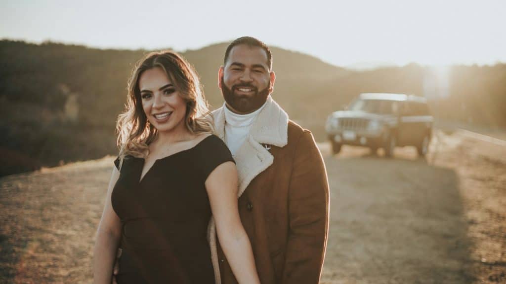 A man and a woman standing next to each other on a dirt road.
