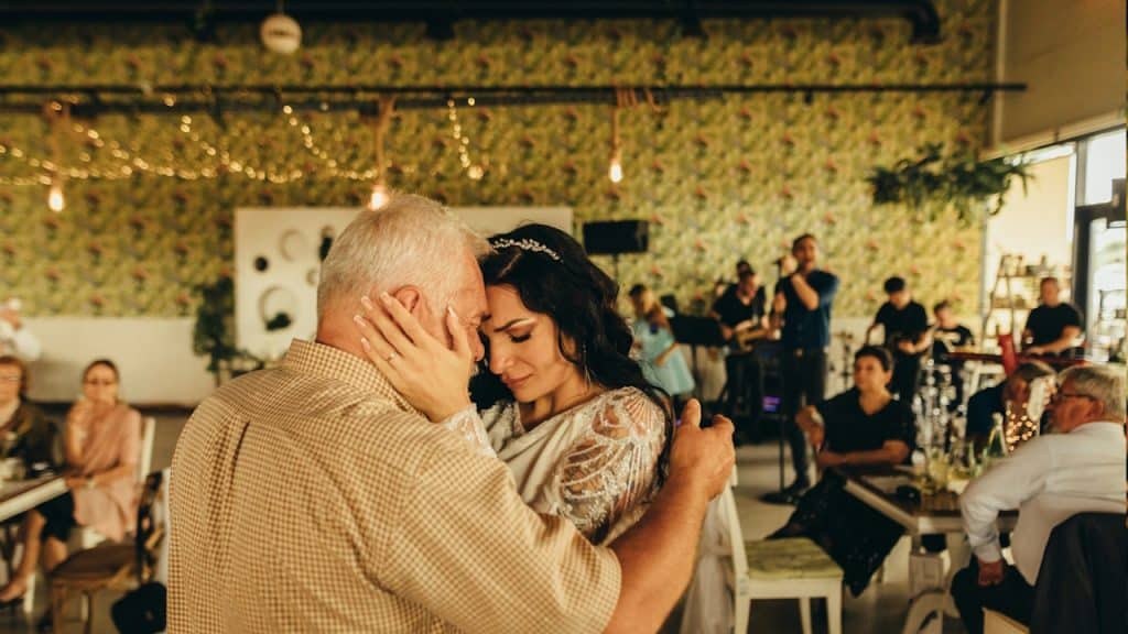 A man and woman embracing each other in a room full of people.