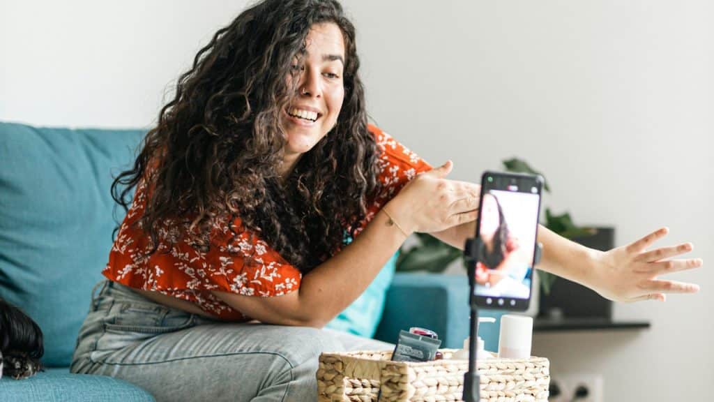 A woman (social media influencer) is making a video while sitting on a couch.