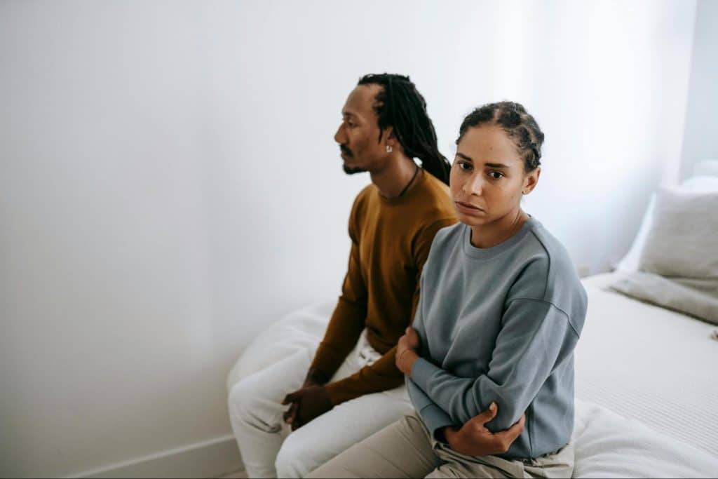 A man and woman at the bed sitting but not talking