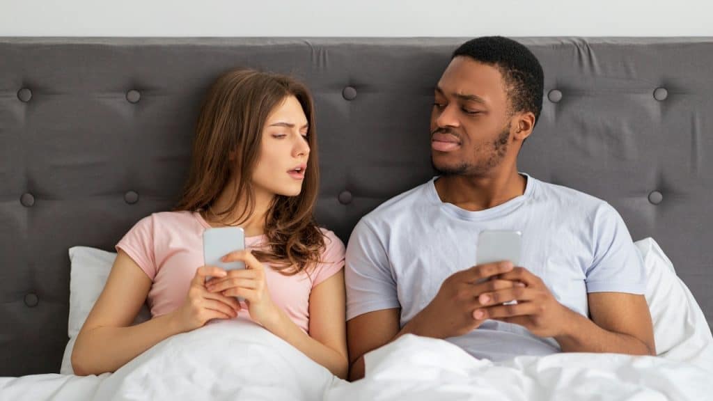 Woman looking at her husbandโs phone.