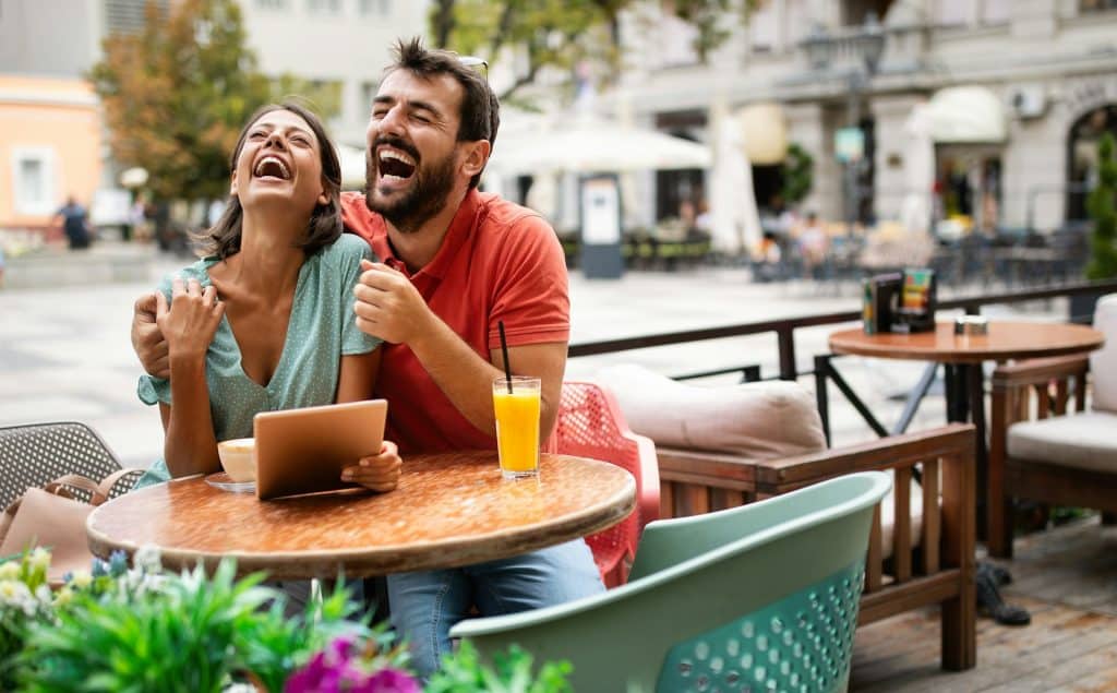 A couple laughing together while spending time at a café.