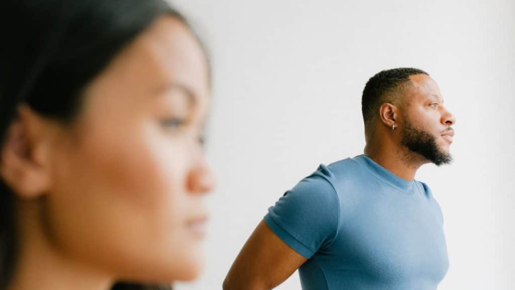 Man in a blue shirt looking away from a blurry foreground woman indoors.