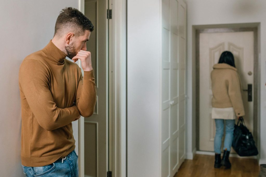 A man watching the woman walk out of the apartment.