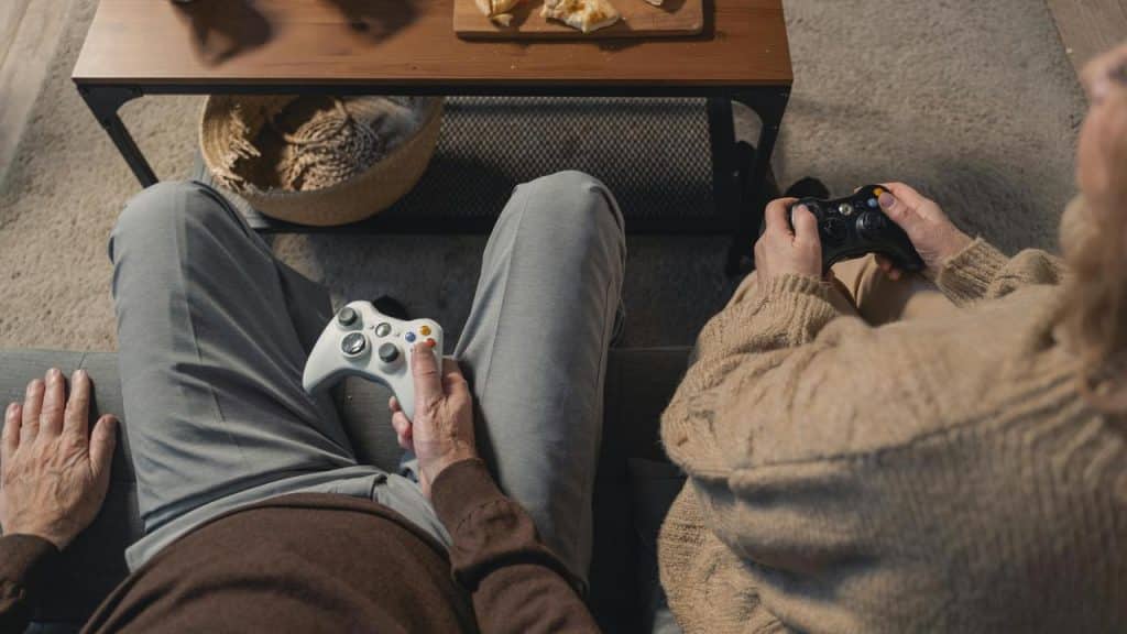 A pair of people sitting on a couch playing video games with controllers.