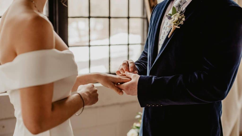 A groom places a ring on the brideโs finger during a wedding ceremony.