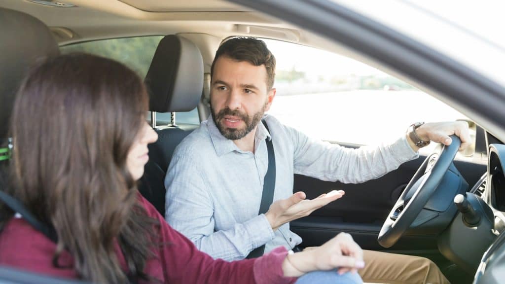 A man driving while quarreling with a woman in the car.