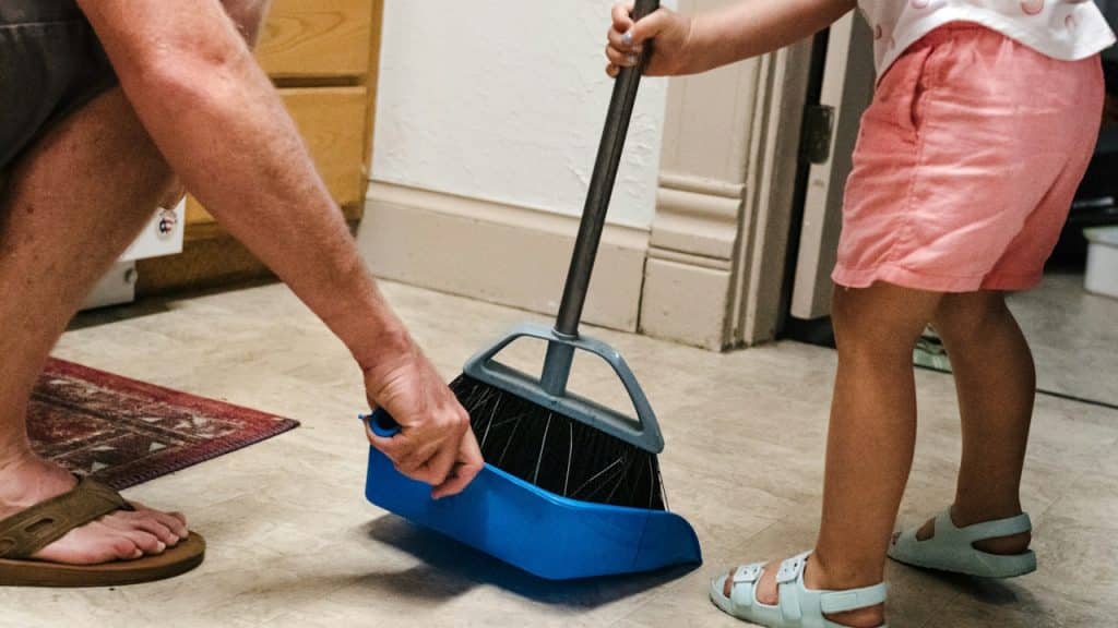 A man and his little daughter are cleaning the floor of the house.