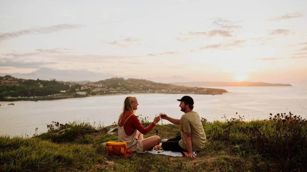 A couple enjoying a picnic together on a sunset cliffside.