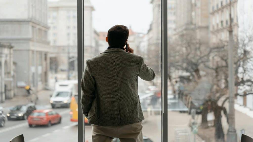 A man looking out the window while on the phone