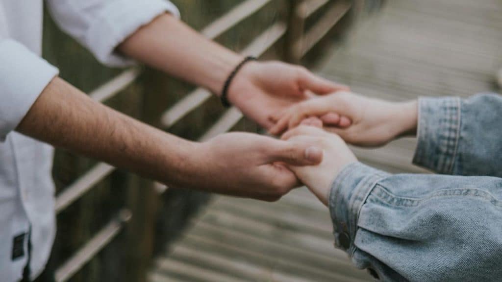 A couple holding each other’s hands outside.