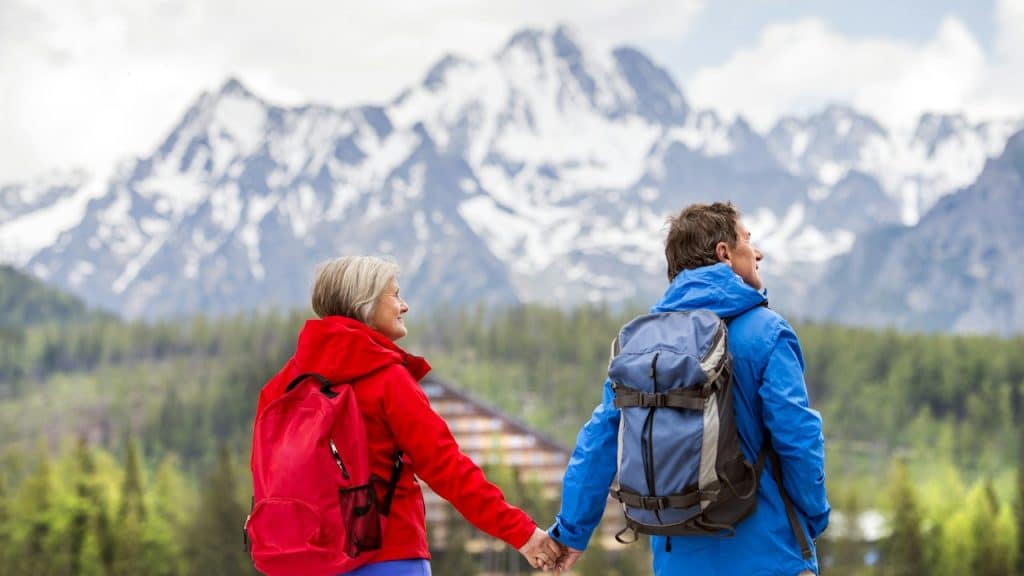 A senior couple during the walk in beautiful mountains and hills in the background.