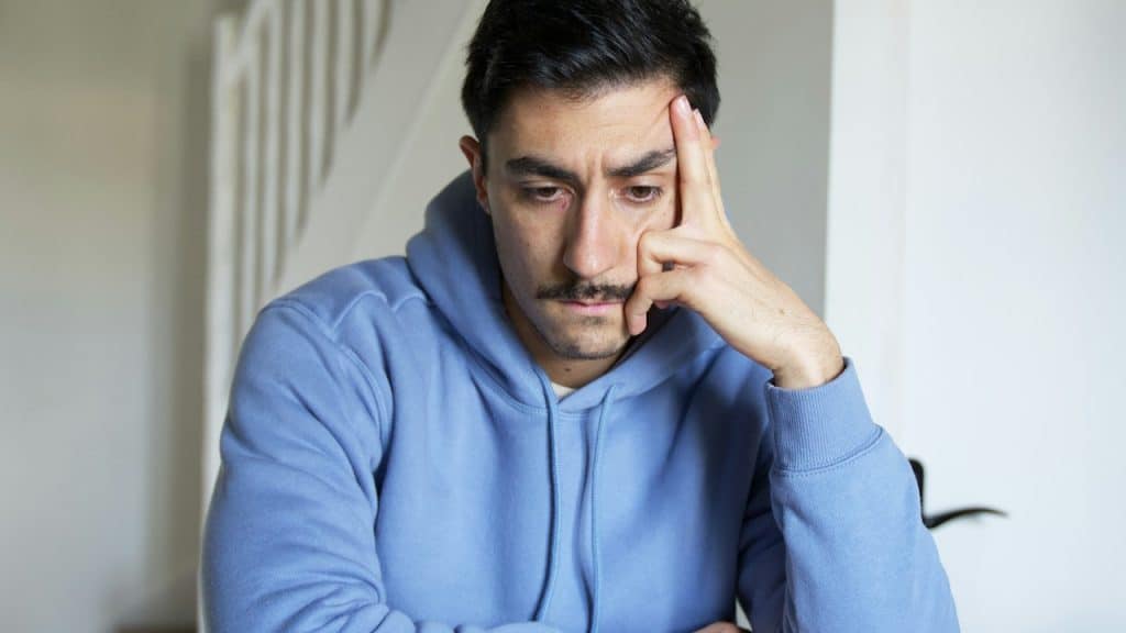 A man sitting at a table with his hand on his face.