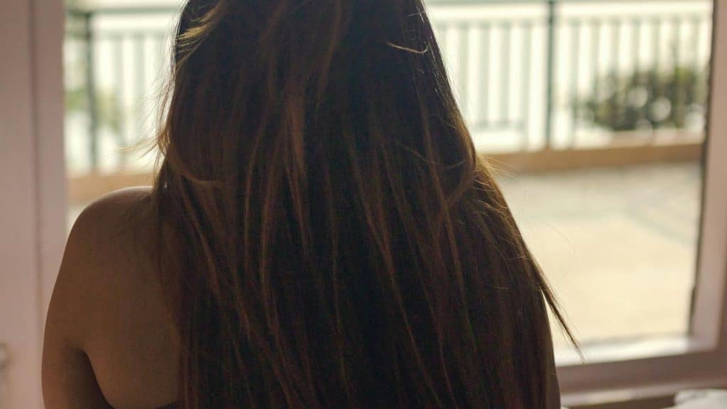 A woman with long hair standing by a balcony.