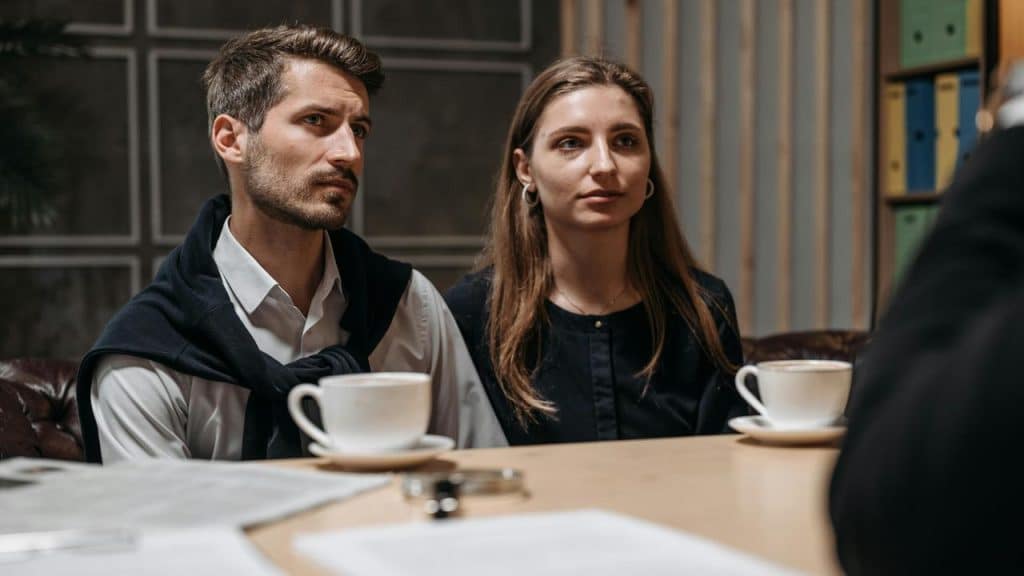 A couple sitting at a table with coffee cups during a serious conversation.
