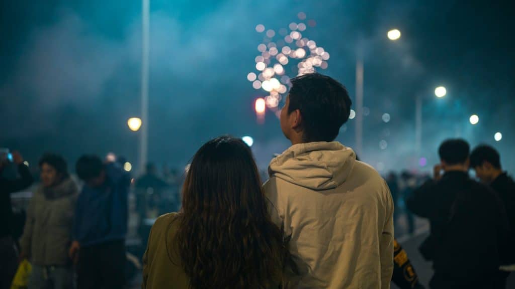 A couple watching fireworks at night together.