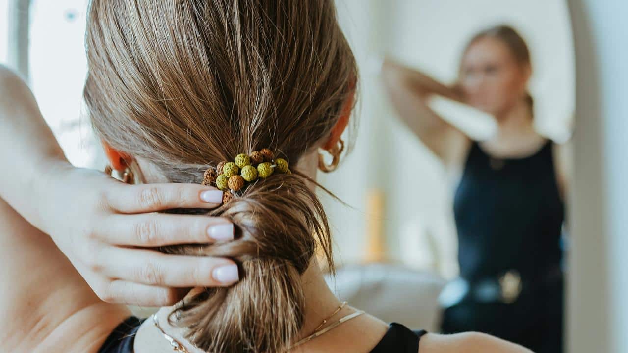 A woman adjusting her hair while looking in a mirror.