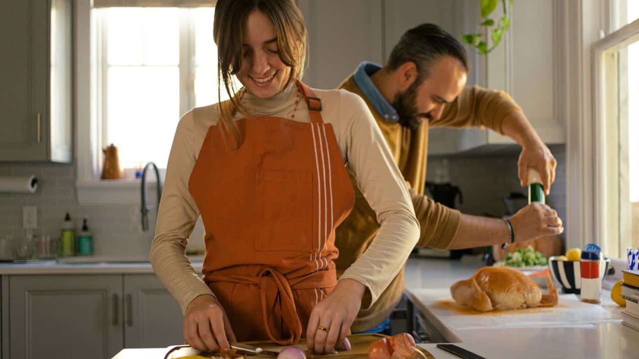 A woman and a man are cooking together in a bright kitchen.