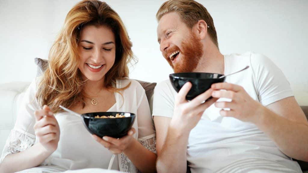 A couple laughing with each other while having breakfast together.