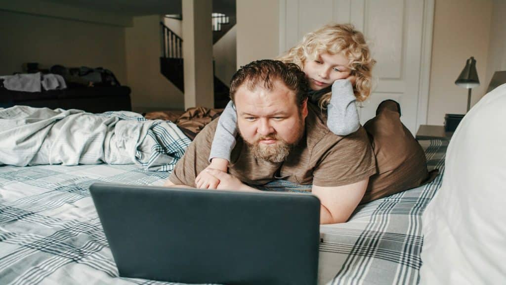 A dad watching something on the laptop with his kid