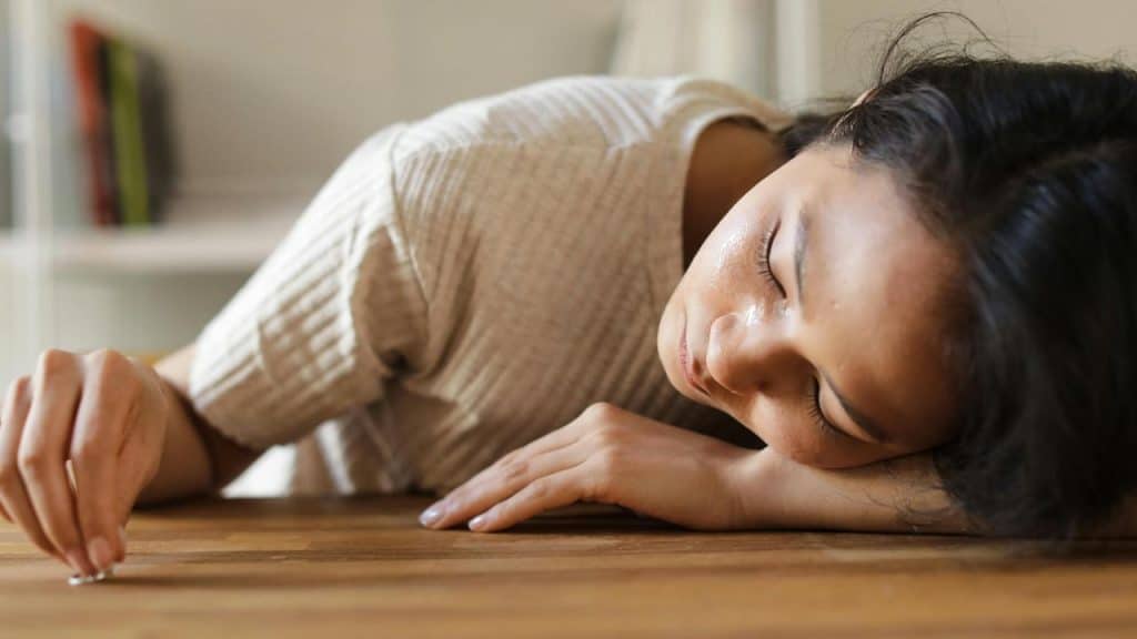 A woman lying with her head on a table, her face streaked with tears.