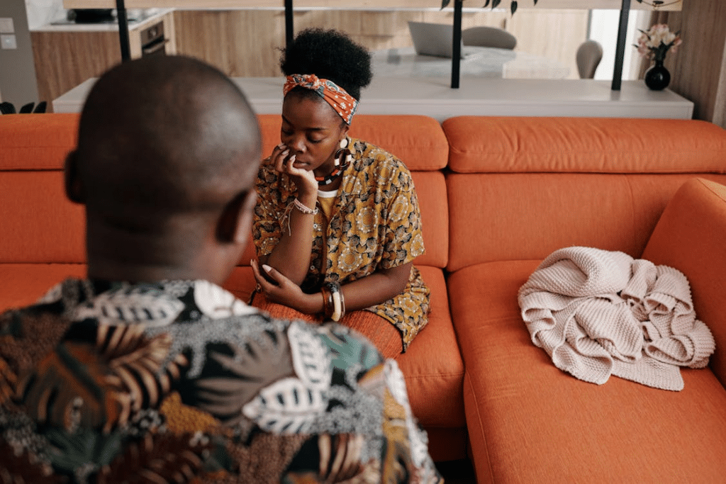 Man Having a Conversation with a Woman Sitting on Orange Sofa