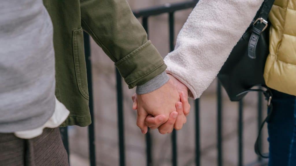 A couple holding hands while walking outdoors.