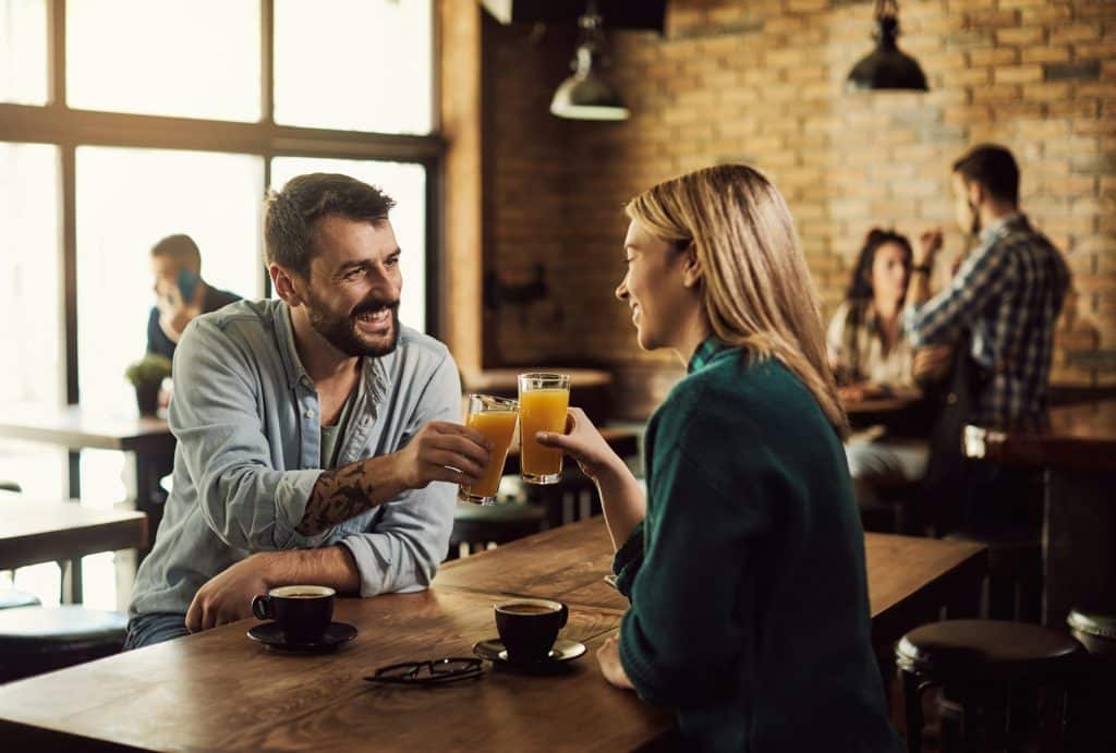 A man toasting with orange juice in a pub.